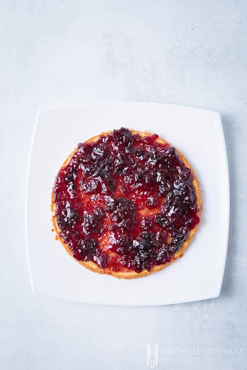 An aerial view of one layer of cake with cherry jam spread on top 