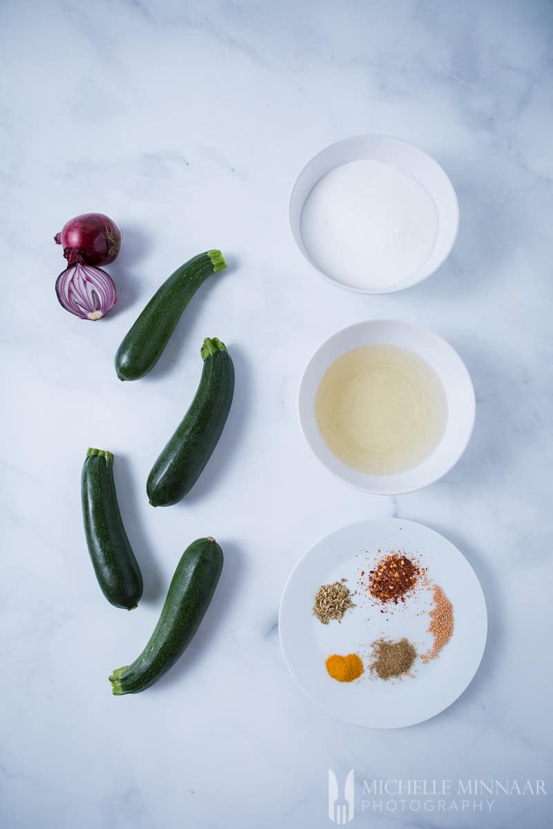 The ingredients for Courgette Pickle on a counter: Courgettes onion spices 