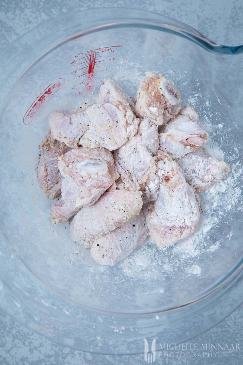 A bowl of raw chicken wings dusted with flour to make air fryer chicken wings