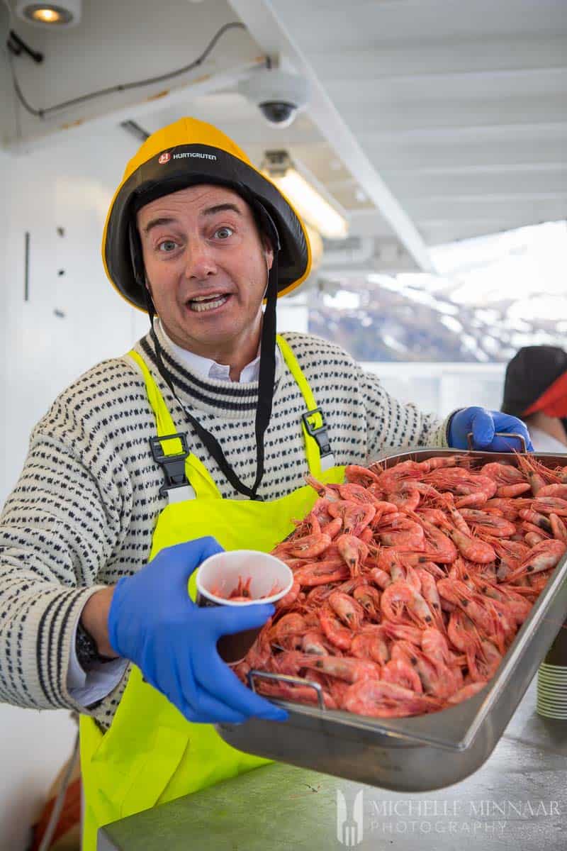 A fisherman holding a large tray of raw pranws