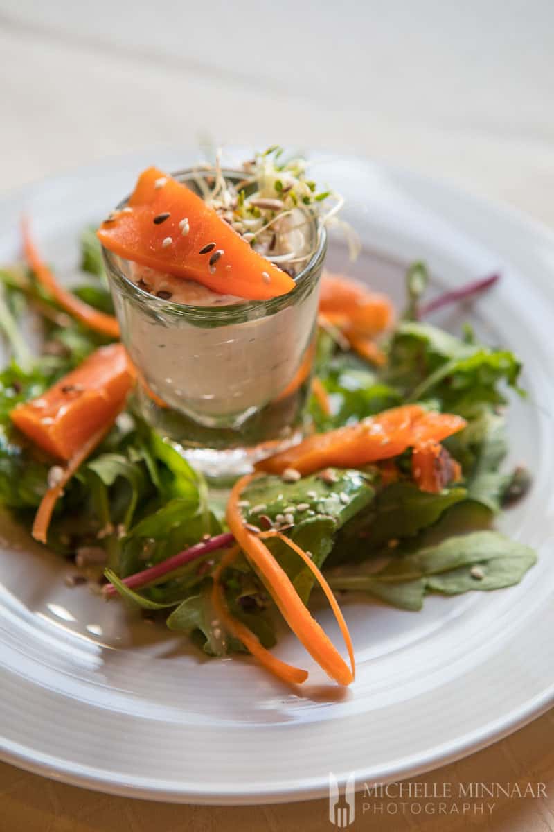 A close up of an orange appetizer in a small shot glass