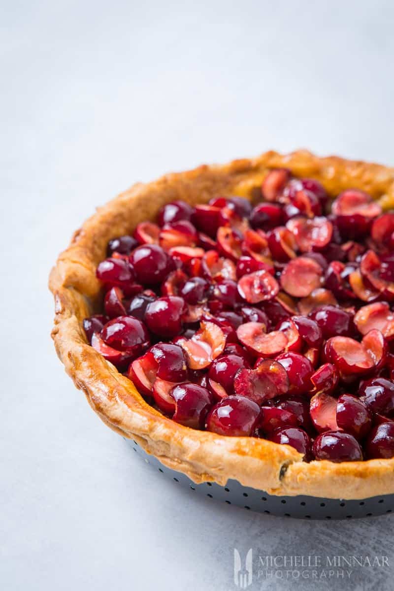 A close up of cherry pie filling inside of a brown pie crust