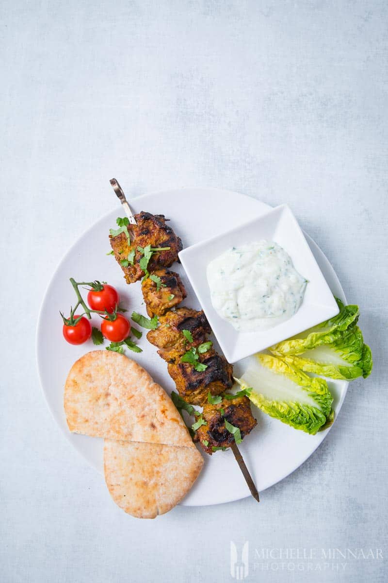 Eine komplette Mahlzeit aus Lamm-Tikka, Tomate, Salat, Lammspieß und Joghurt-Dip