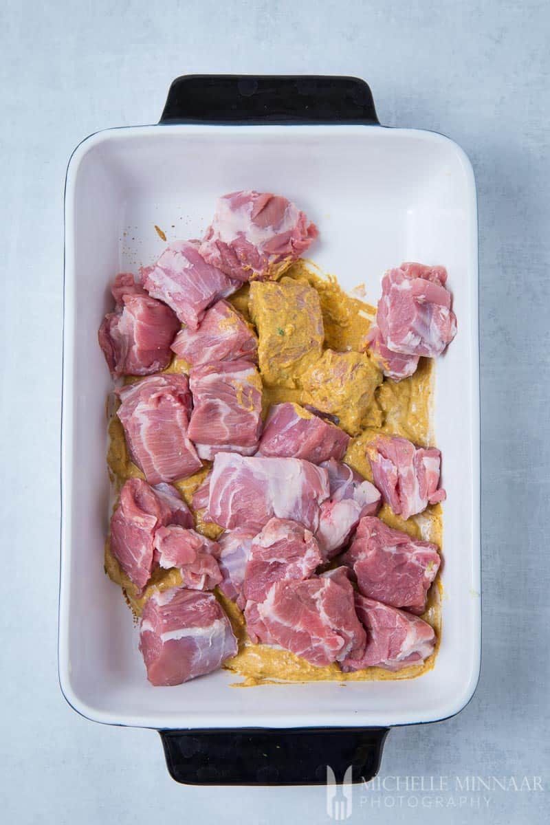 Chunks of lamb in a pan with a brown tikka sauce on it