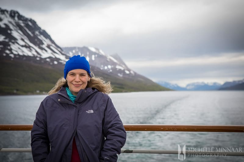 Michelle standing on the ship with mountains in the background 