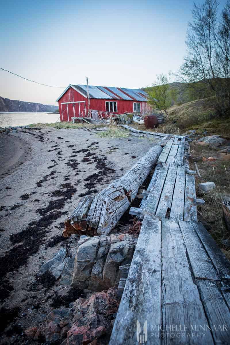 A red barn, sand, trees and a long wooden plank 