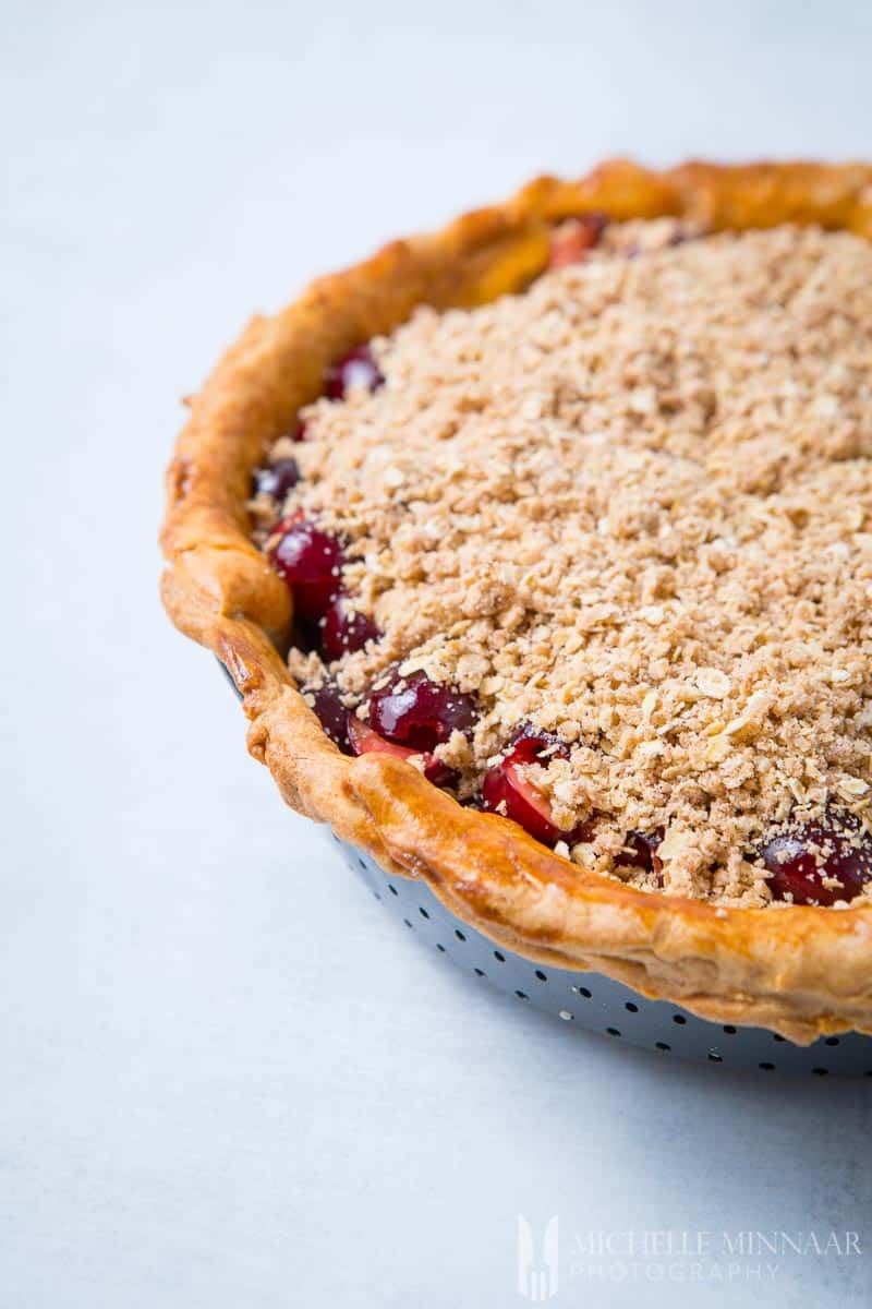 A cherry crumble pie covered in crumbs, ready to go into the oven