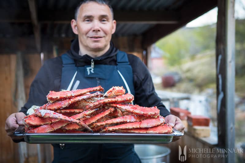 A man holding a platter of steamed crab legs