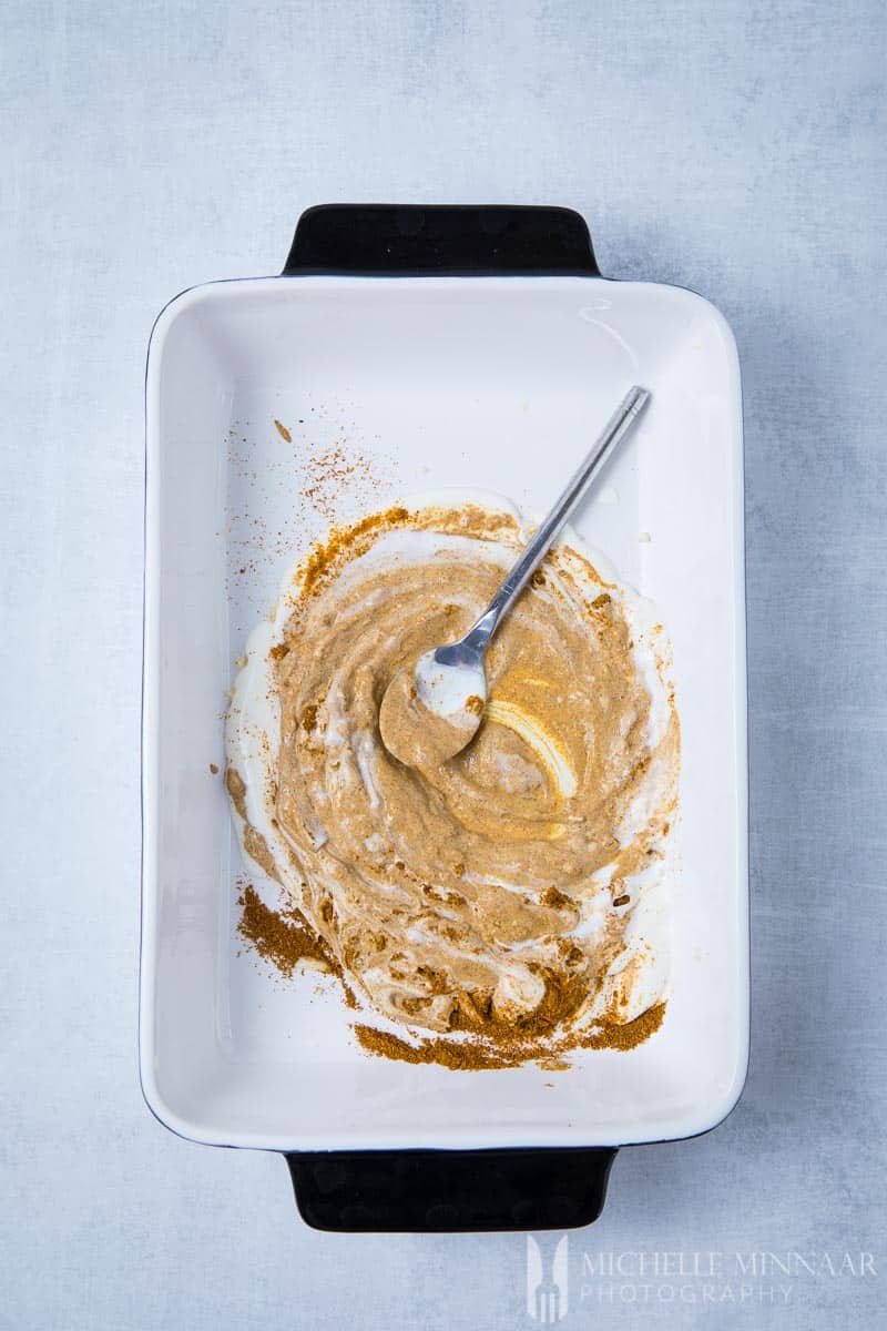 Yogurt Marinade spread all over the bottom of a white baking dish 