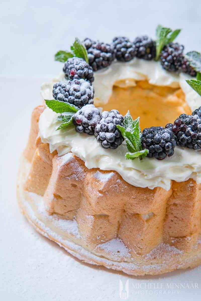 A sugar free angel food cake topped with blackberries and powdered sugar