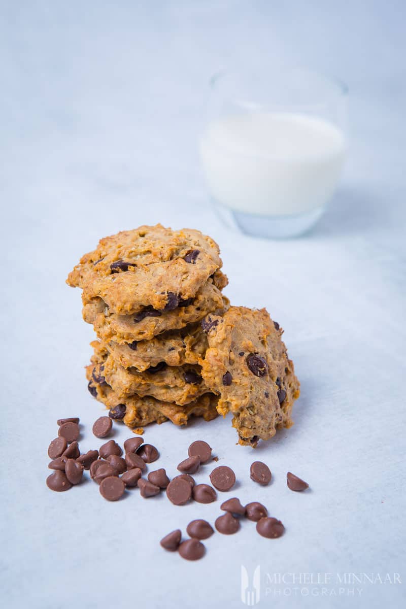 A tall stack of sugar free chocolate chip cookies and chips and milk 