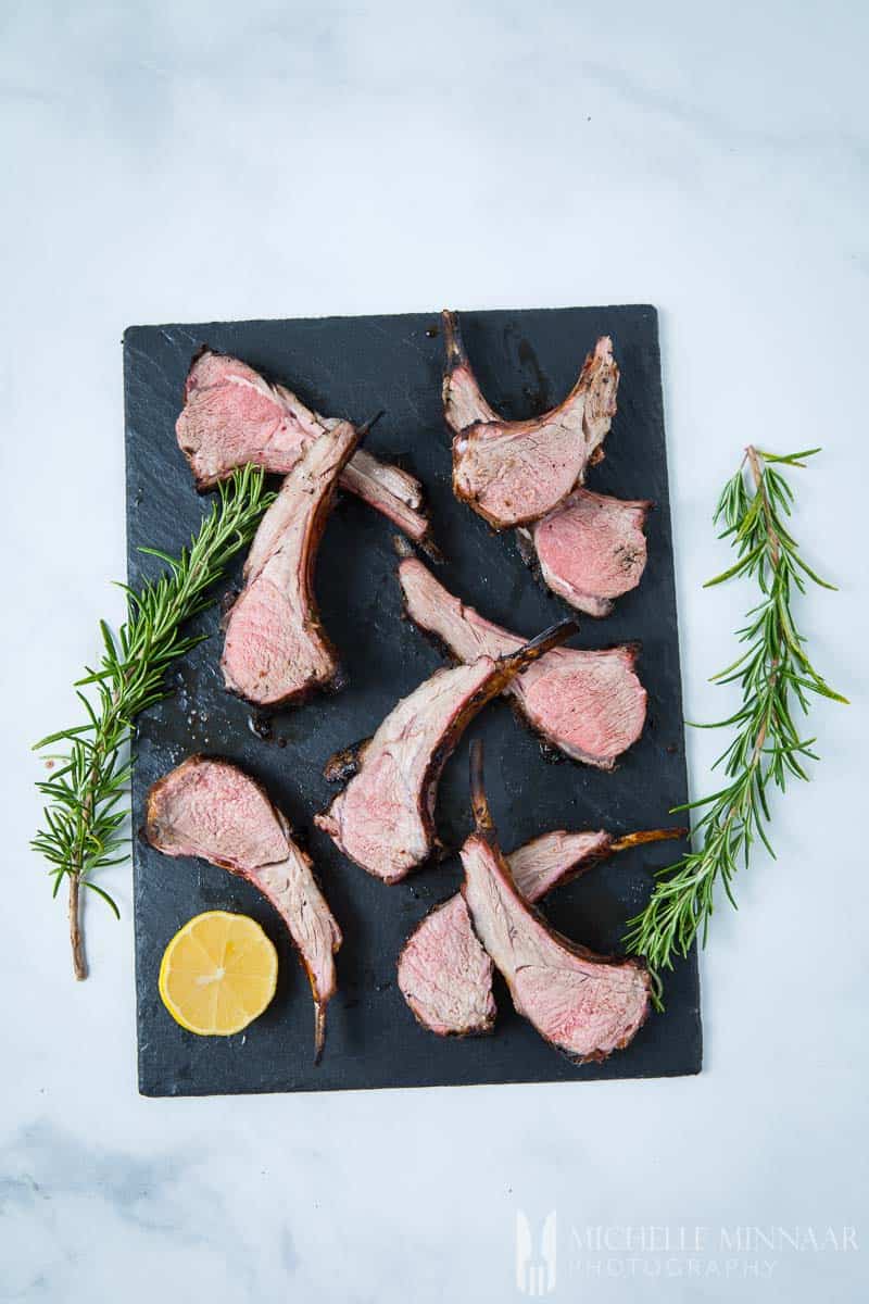 BBQ rack of lamb on a grey slab with rosemary sprigs