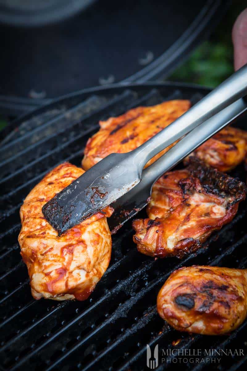 A piece of chicken on a grill with bbq on it for smoked chicken breasts