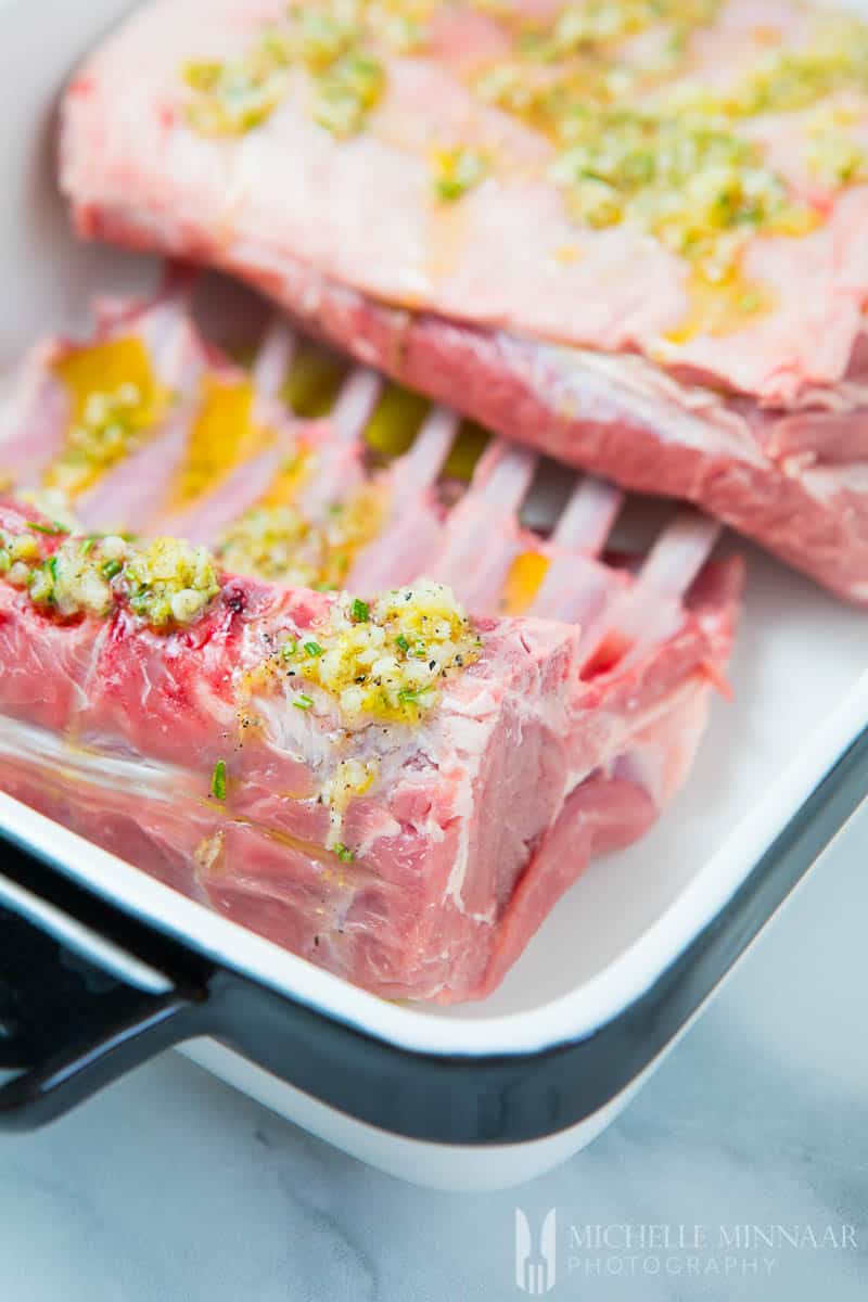 A close up of raw lack of lamb with a rosemary mixture on top