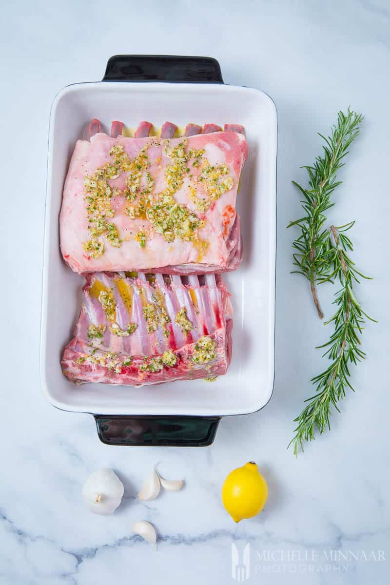 Two raw racks of lamb in a cassarole dish