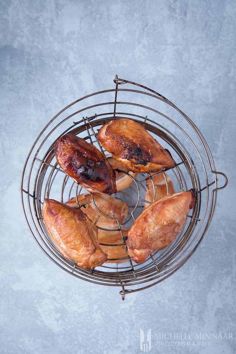 A wire basket full of smoked chicken breasts