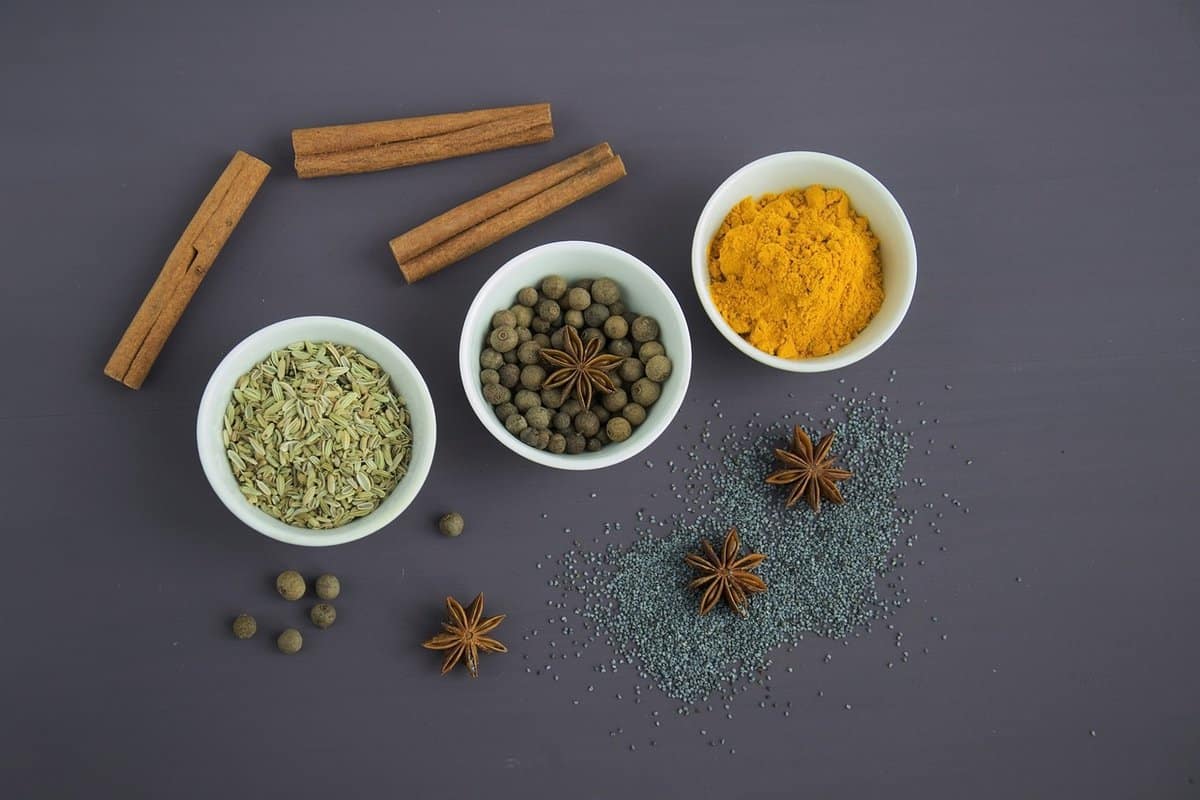 Three bowls of spices and anise seeds around them