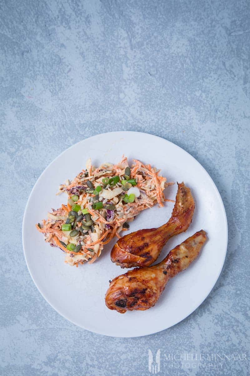 Two smoked chicken drumsticks on a plate with coleslaw 
