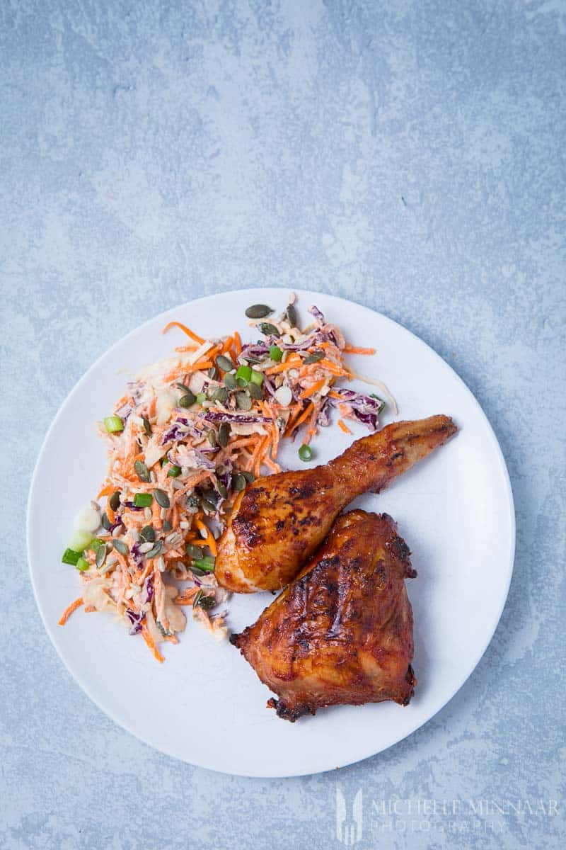 Two pieces of chicken on a plate with coleslaw 