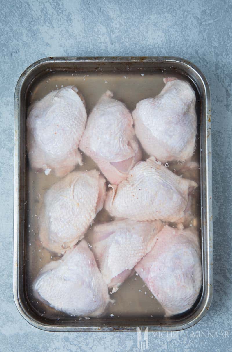 Raw chicken thighs in a brining liquid 