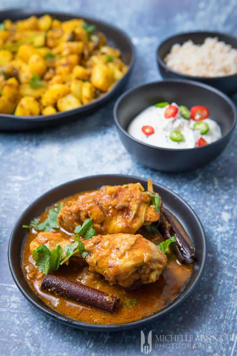 A bowl of chicken kasha with three indian side dishes