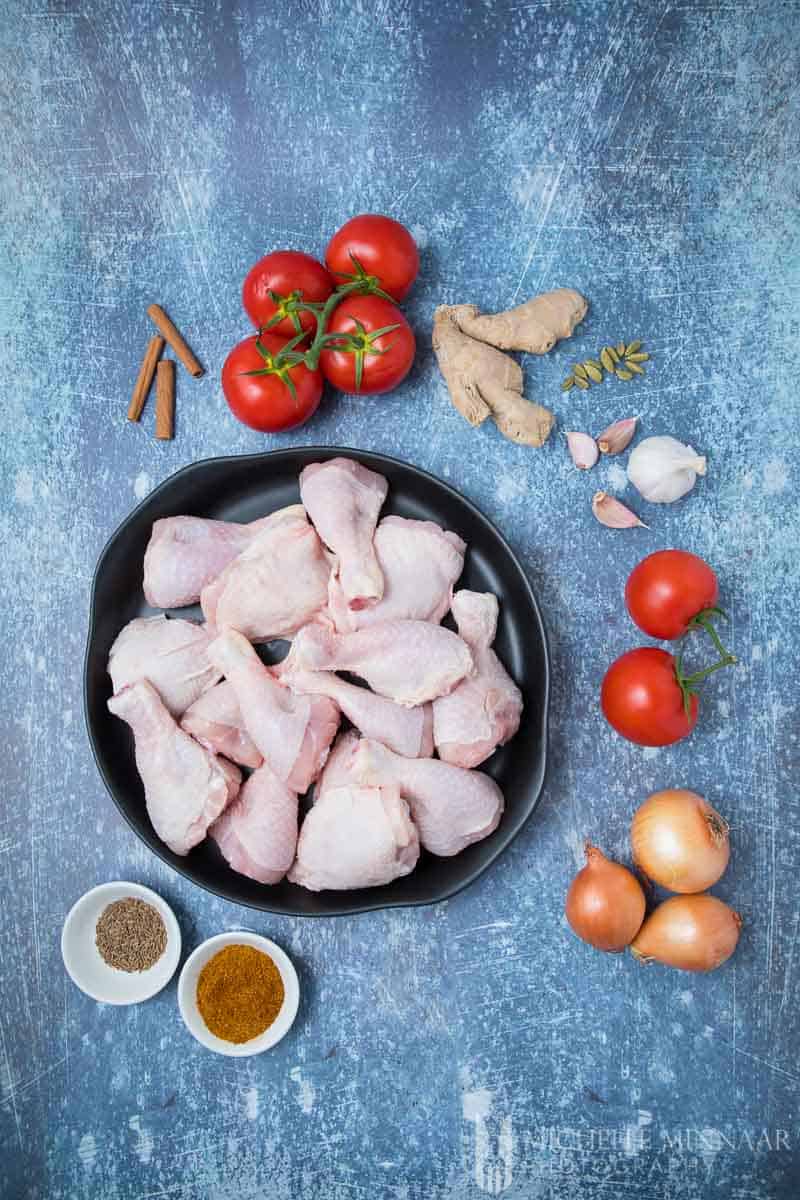 Ingredients for Chicken Kasha - raw chicken in a bowl, spices, onions, tomatoes