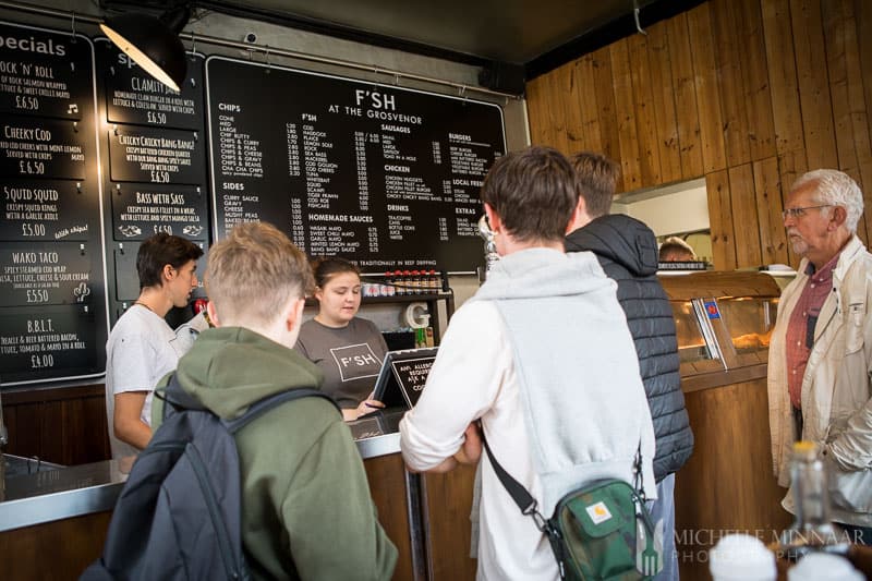 People standing at a counter at the Grosvenor Fish Bar Norwich