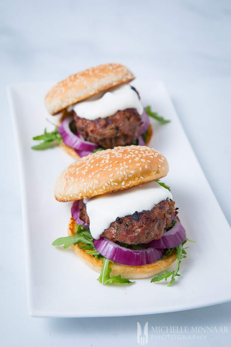Two minted lamb burgers on a white plate