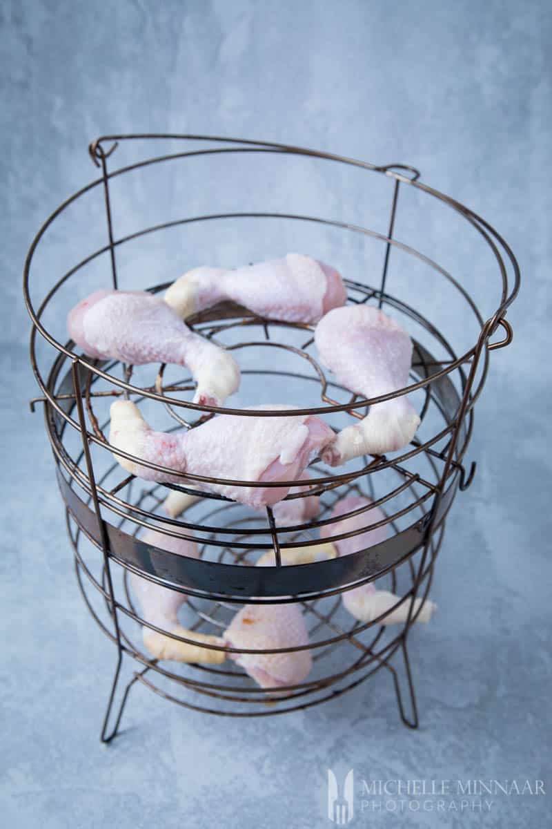 Raw Chicken Drumsticks in a wire cage