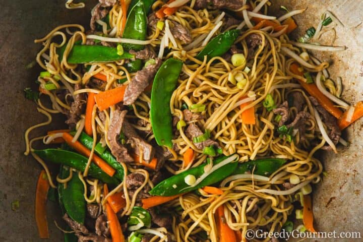 Frying noodles, beef and veg in a pan.