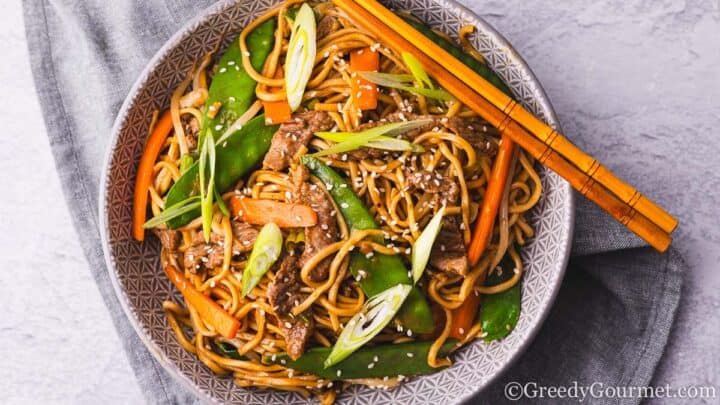 Beef chow mein in a bowl with chopsticks.