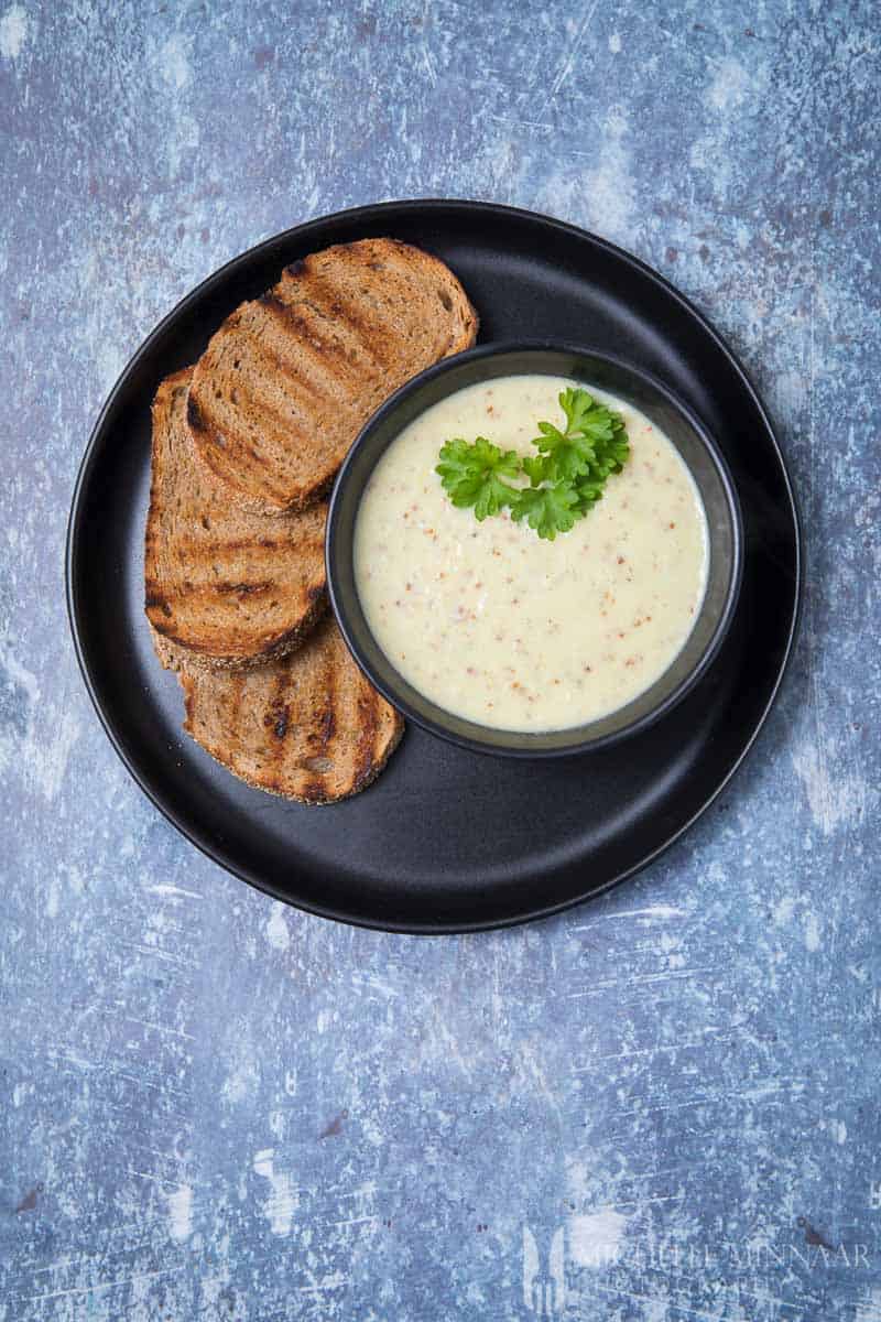 A bowl of brown soup and three sliced of toast 