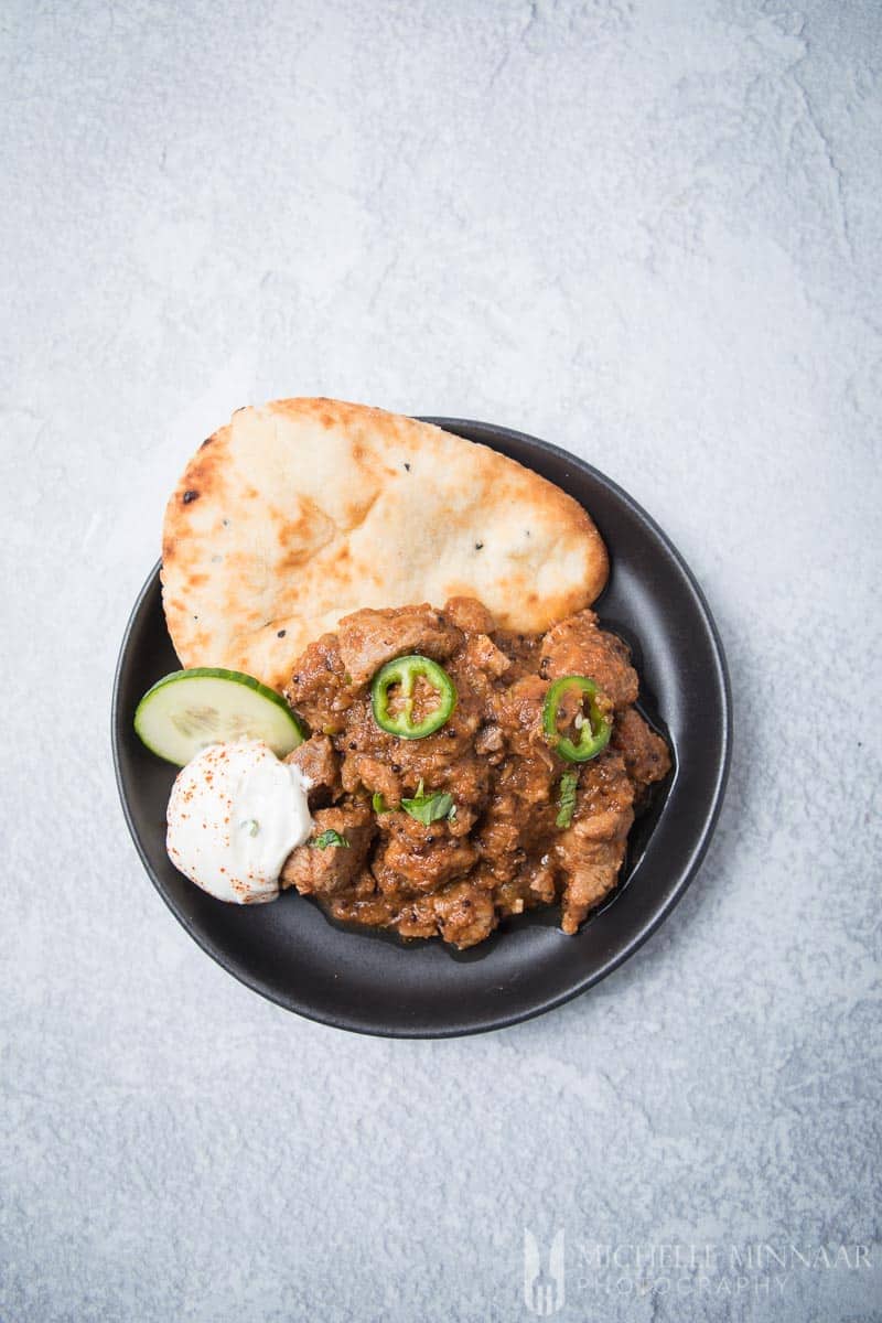 A small plate of lamb bhuna, rotti and raita 