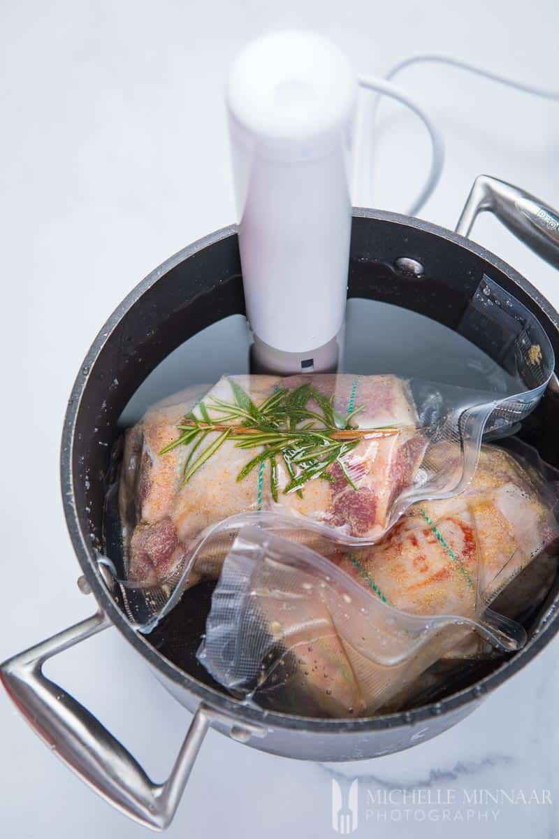 Lamb shoulder wrapped in plastic in a bowl with water and the sous vide