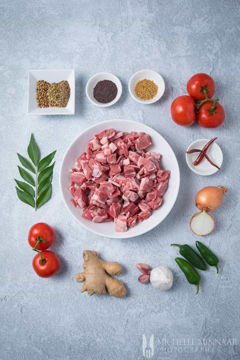 Ingredients to make lamb bhuna: raw lamb, tomatoes, garlic, peppers, ginger and onions 