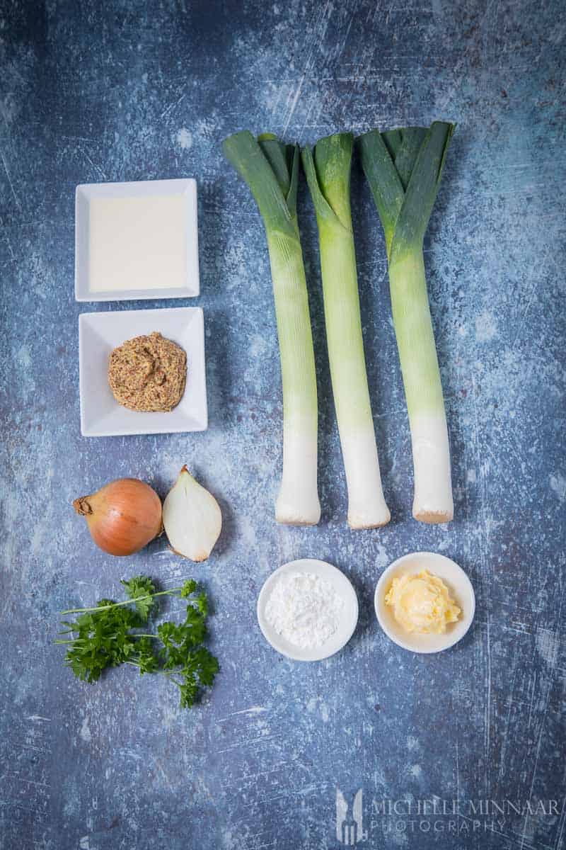 Ingredients for mustard soup: Mustard, Cream, Flour, Onions, Parsley, Leeks on a counter