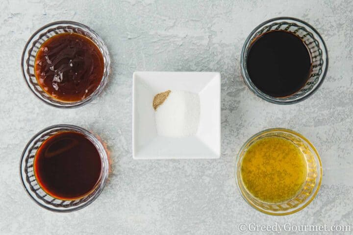 Oyster sauce, soy sauce, wine, sugar and pepper in bowls.