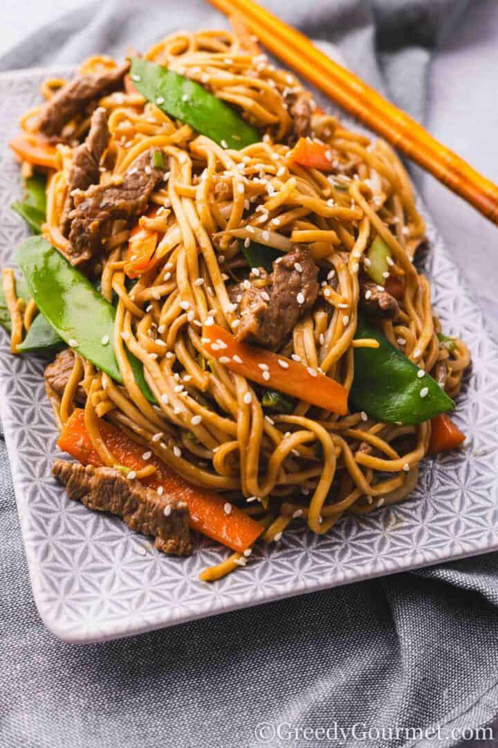 Beef chow mein on a plate with chopsticks.