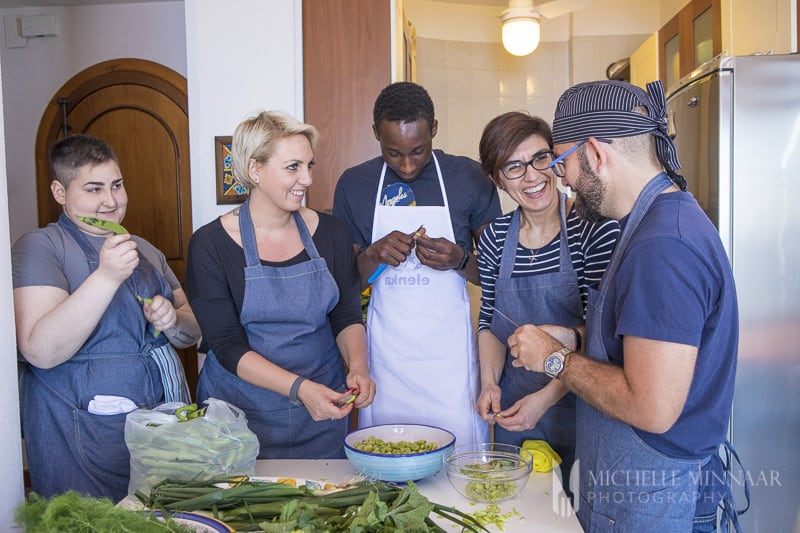 Five chefs standing around a table cooking squid ink risotto