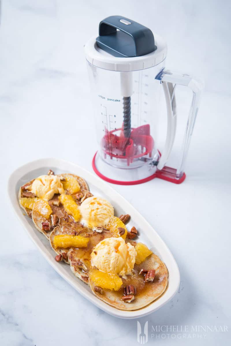 The blender with a plate of pancakes next to it