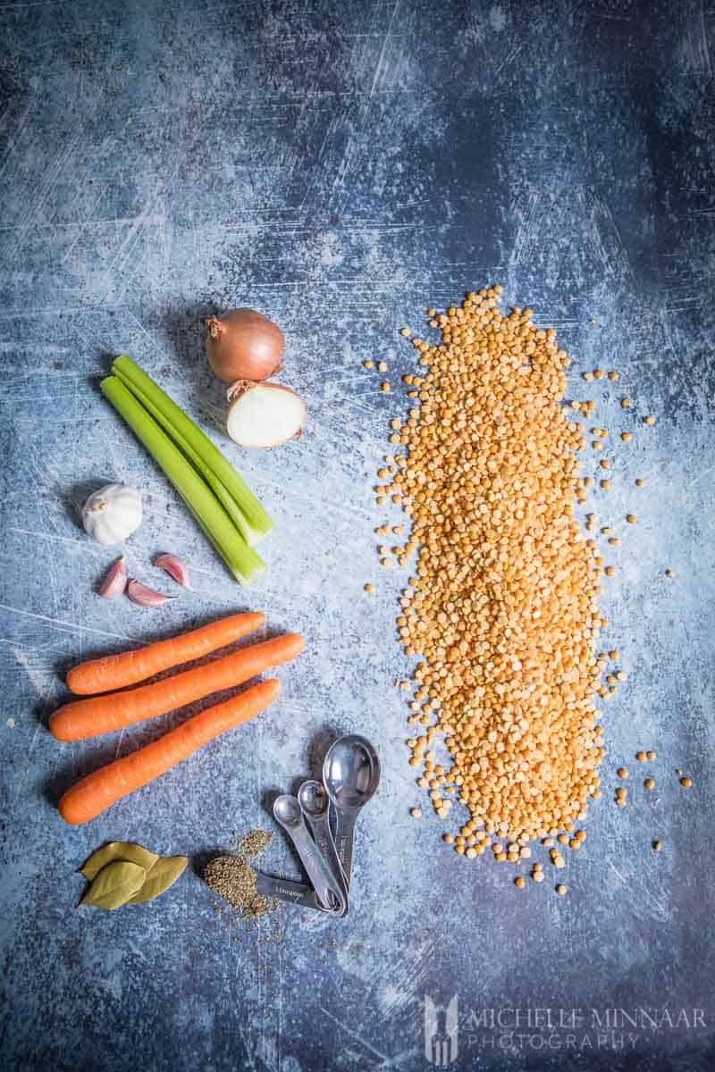 Ingredients to make vegan split pea soup on a counter: Celery Carrot Onion Split Peas