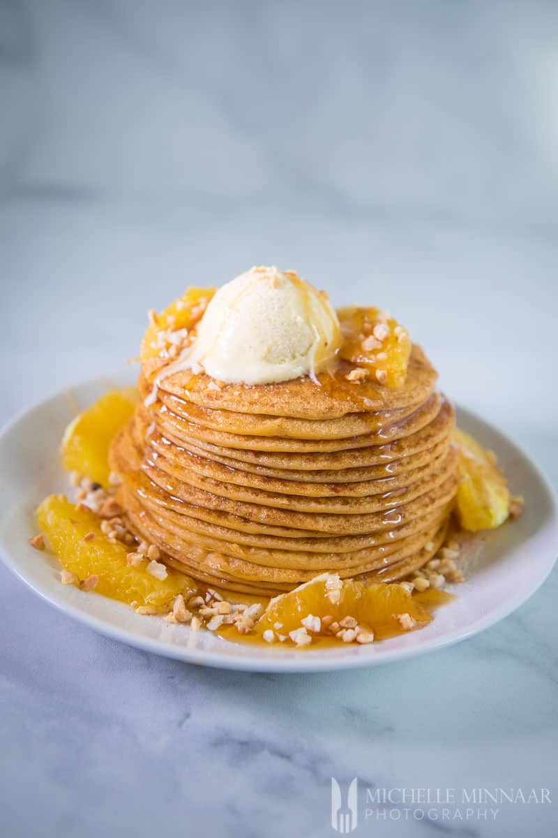 A tall stack of vegan sweet potato pancakes with a scoop of ice cream