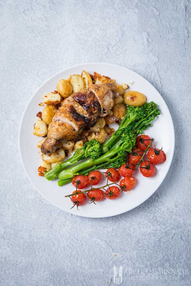 An aerial view of chicken ballotine, broccoli and tomatoes