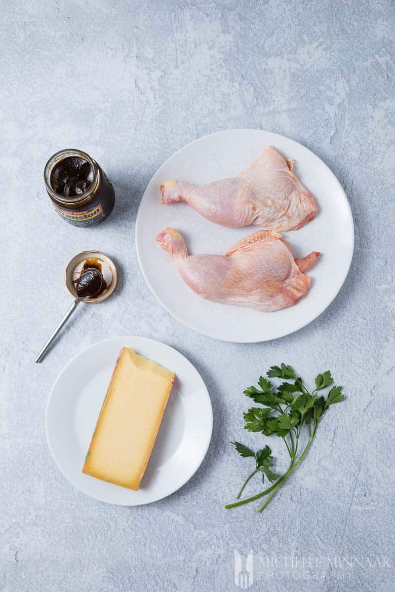 Raw chicken, a block of cheese and an open jar of branston pickle on a counter