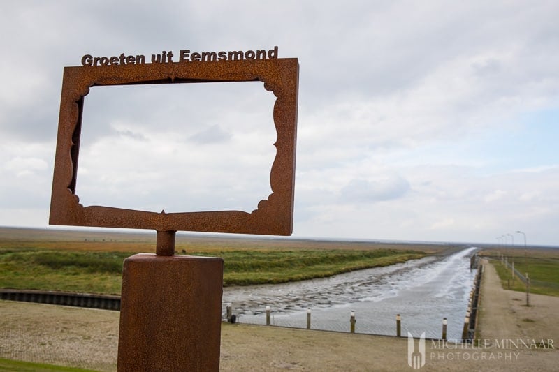 A brown sign with a river in the background