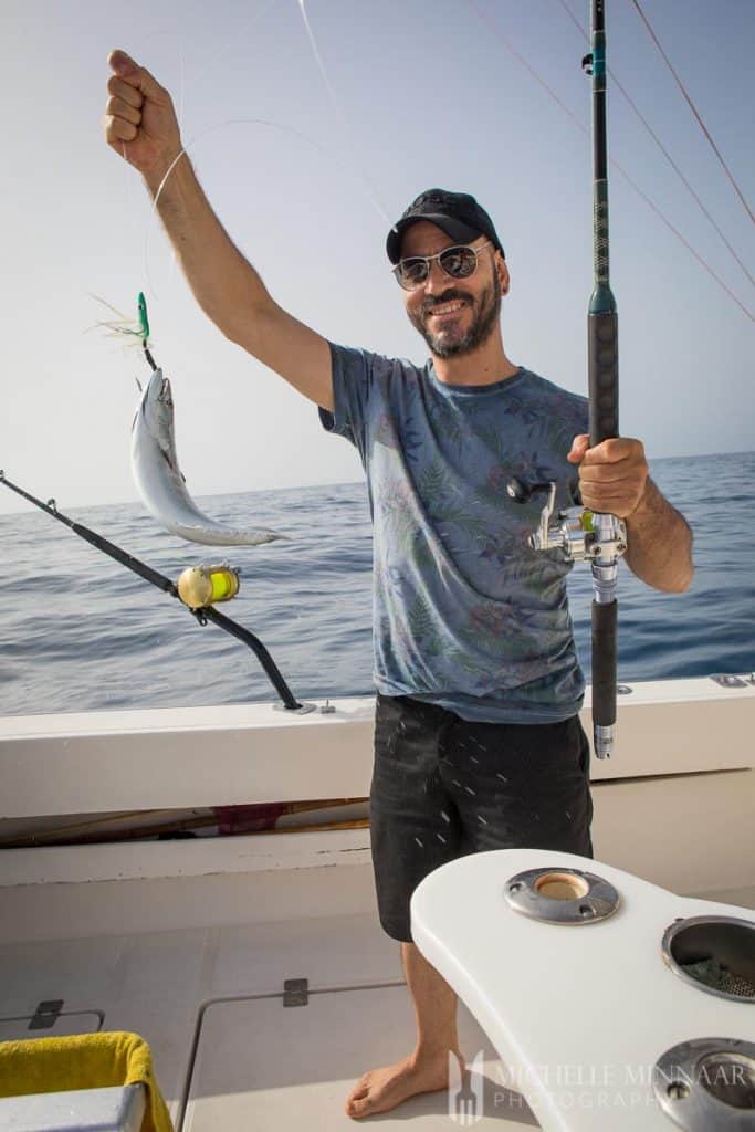 A man holding a piece of fish from a fishing rod