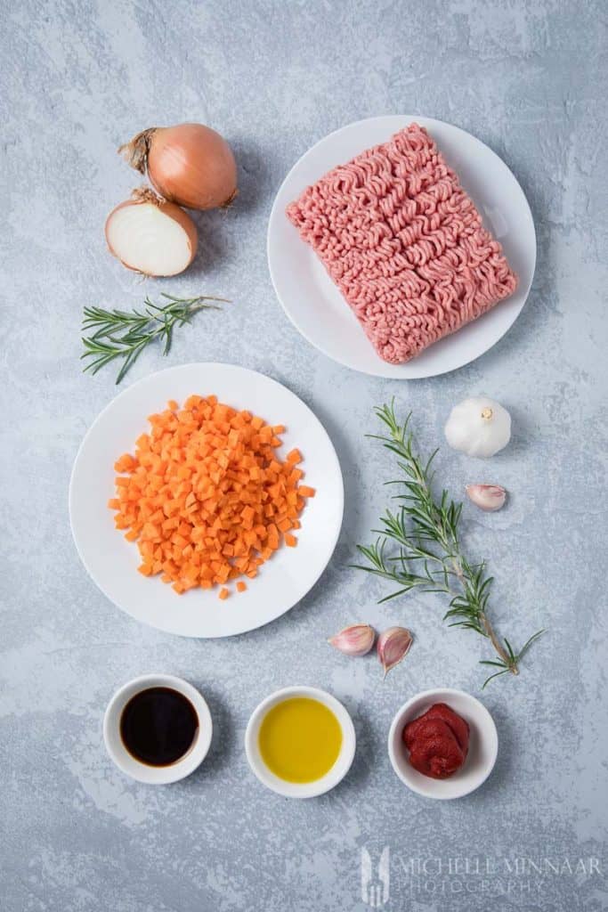 Ingredients to make lamb mince: raw lamb, carrots, onions, garlic