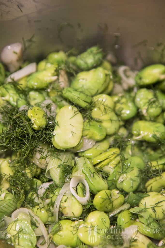 A close up of green broad beans and onions 