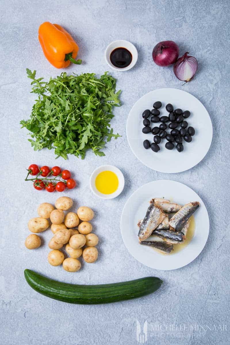 Ingredients to make sardine salad: olives, lettuce, potatoes, sardines, onions, orange pepper