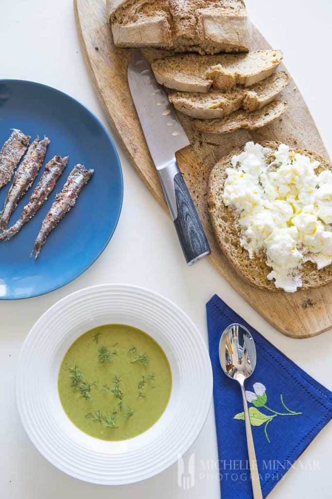 Broadbean Soup, sardines and bread on a table